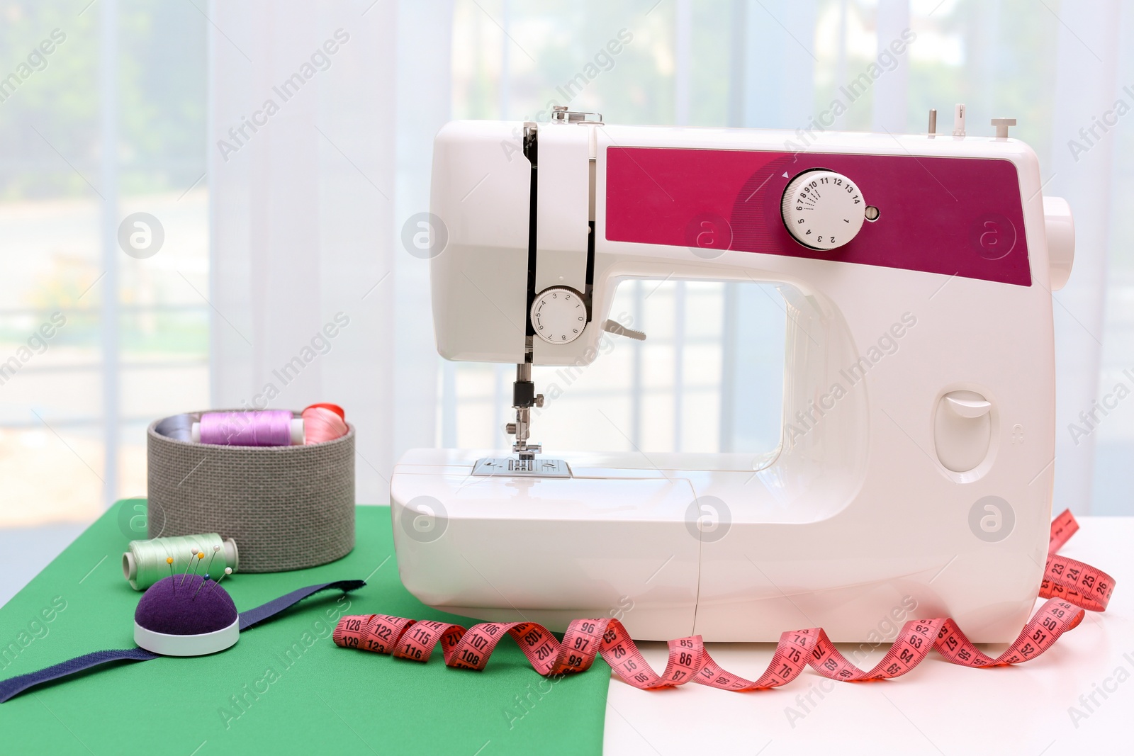 Photo of Modern sewing machine on table near window indoors