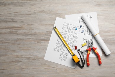 Wiring diagrams and tools on white wooden table, flat lay. Space for text