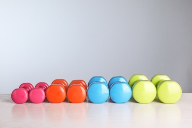 Photo of Many dumbbells for on table against color background. Fitness equipment