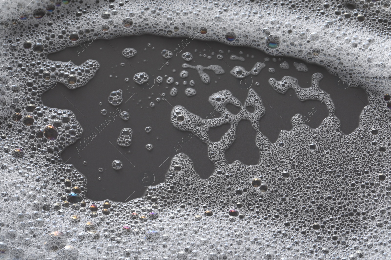 Photo of White washing foam on dark gray background, top view