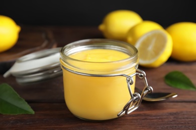 Photo of Delicious lemon curd in glass jar on wooden table