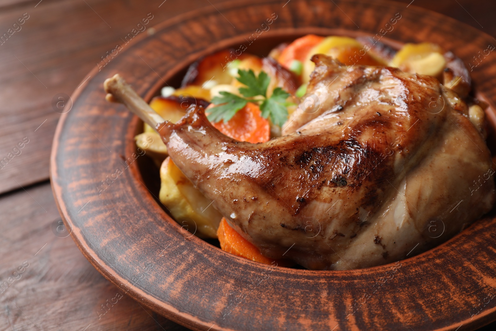 Photo of Tasty cooked rabbit meat with vegetables on wooden table, closeup
