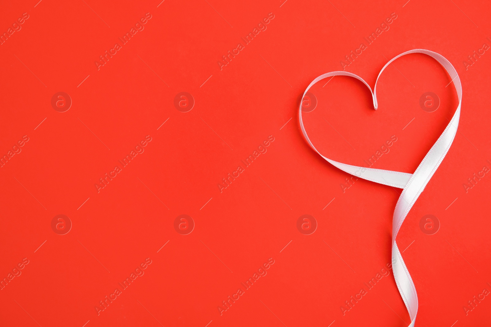 Photo of Heart made of white ribbon on red background, top view with space for text. Valentine's day celebration