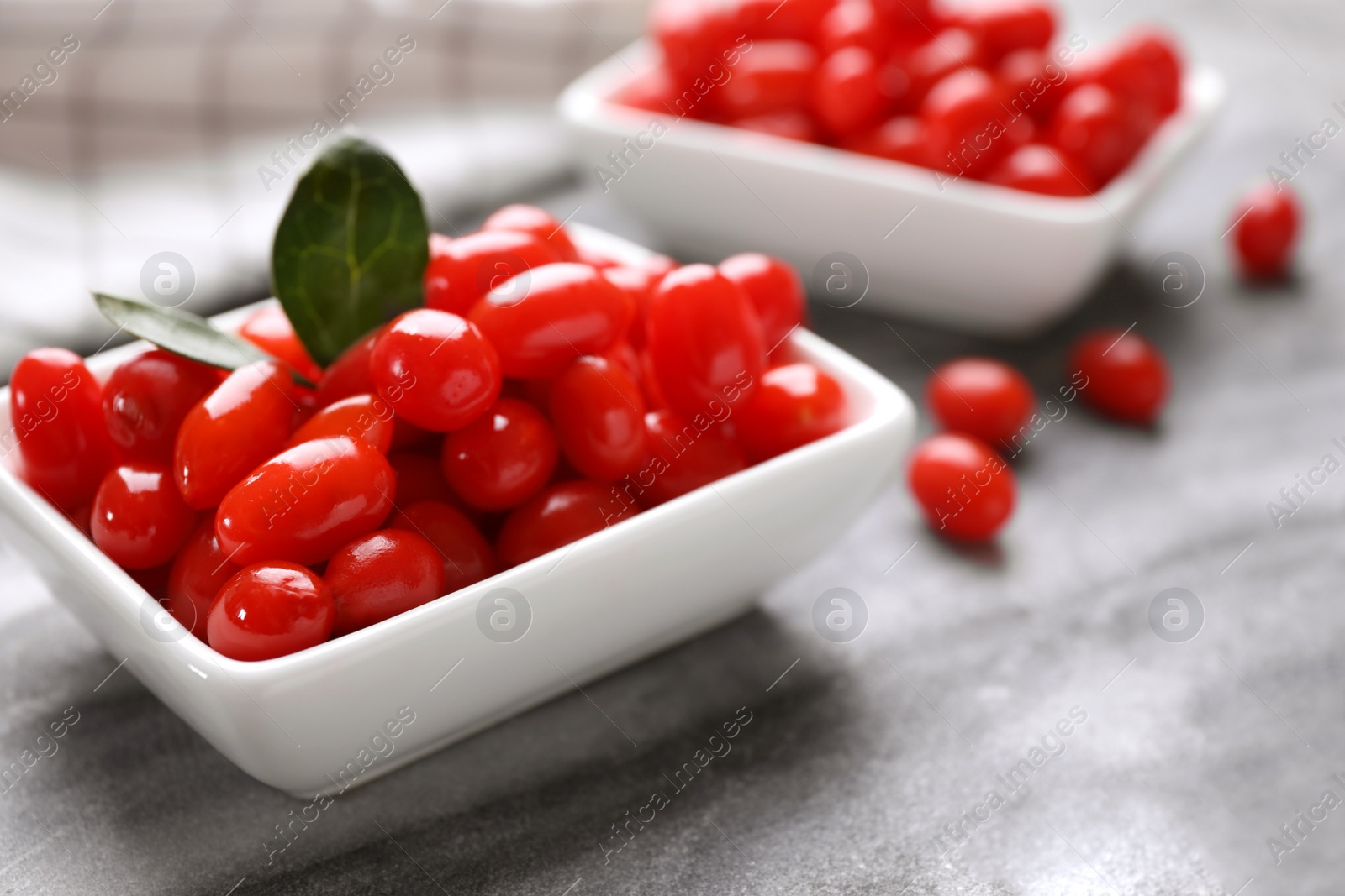 Photo of Bowl with fresh goji berries on grey board, closeup