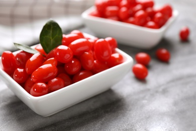 Bowl with fresh goji berries on grey board, closeup