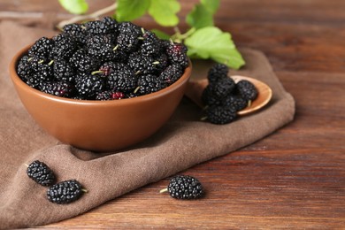 Photo of Delicious ripe black mulberries on wooden table, space for text
