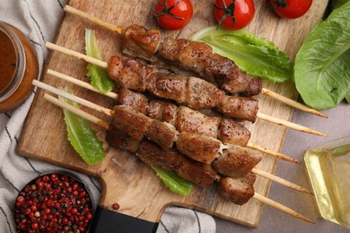 Photo of Tasty cooked marinated meat served with sauce and tomatoes on grey table, flat lay