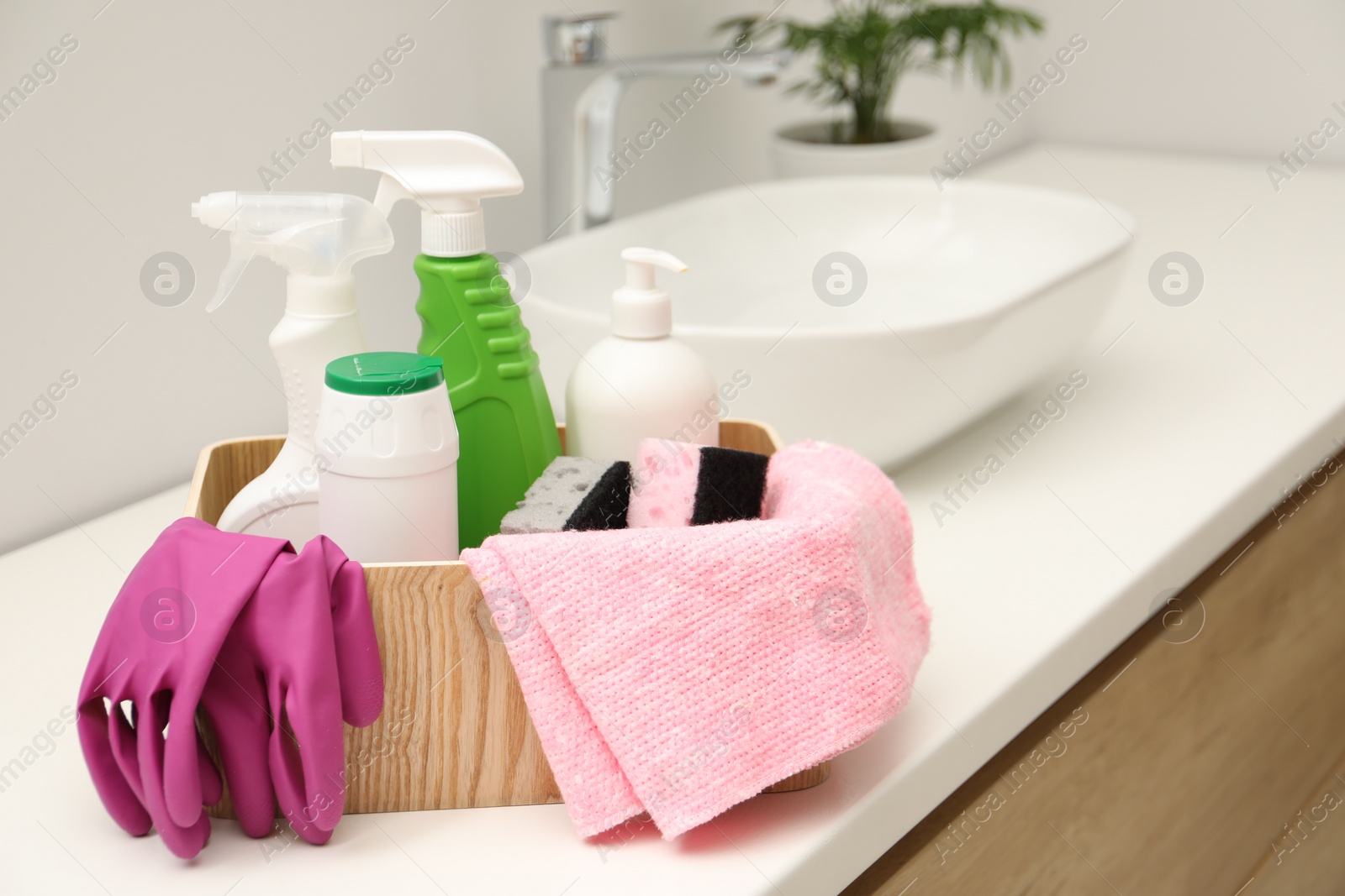 Photo of Different cleaning products in wooden box on countertop indoors
