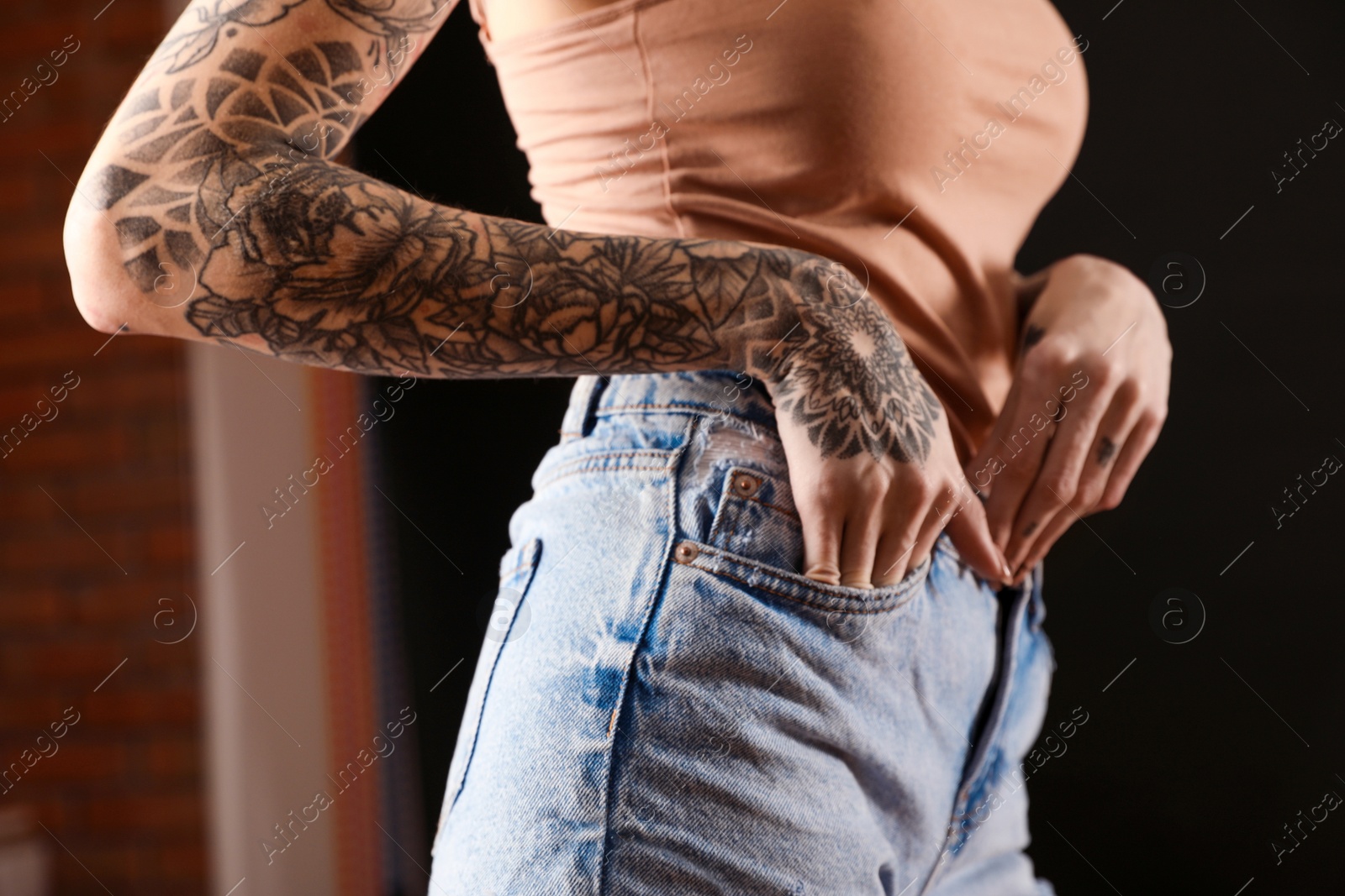 Photo of Woman with tattoos on body against black background, closeup