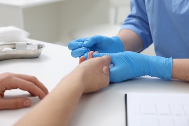 Photo of Laboratory testing. Doctor taking blood sample from patient at white table in hospital, closeup