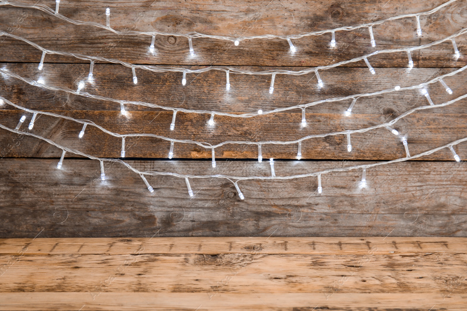 Photo of Beautiful bright Christmas lights on wooden background