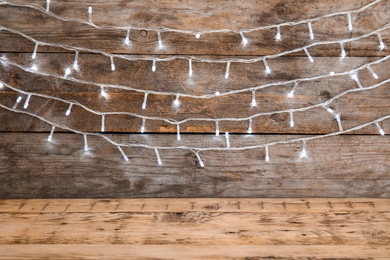 Photo of Beautiful bright Christmas lights on wooden background