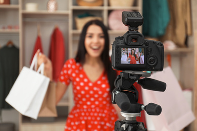 Photo of Fashion blogger recording new video in room, focus on camera