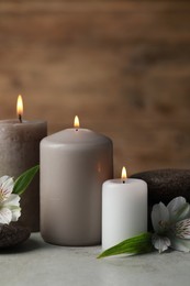 Photo of Beautiful composition with burning candles, spa stones and flowers on light grey table