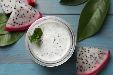 Photo of Delicious pitahaya smoothie, fruit and fresh mint on light blue wooden table, flat lay