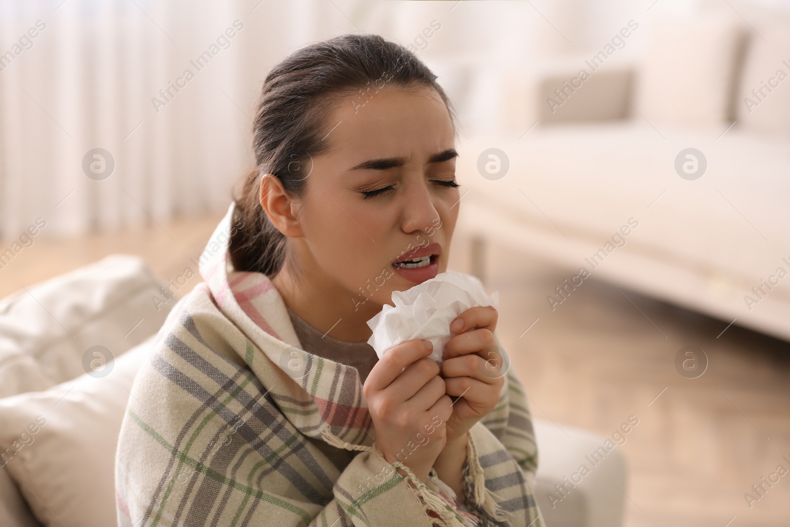 Photo of Young woman suffering from runny nose in living room