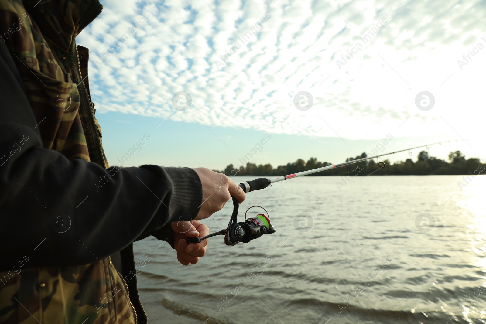 Photo of Fisherman with rod fishing at riverside, closeup