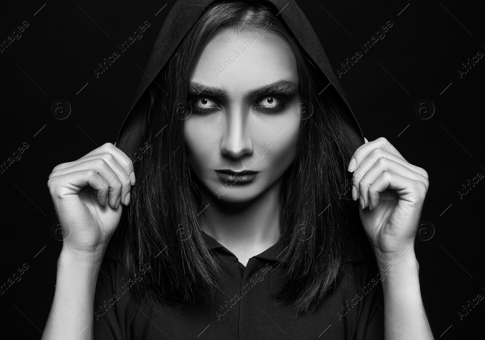 Photo of Mysterious witch with spooky eyes on dark background. Black and white effect