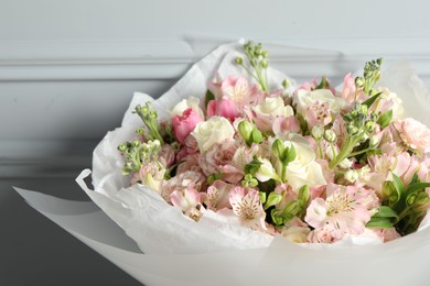 Photo of Beautiful bouquet of fresh flowers near grey wall, closeup