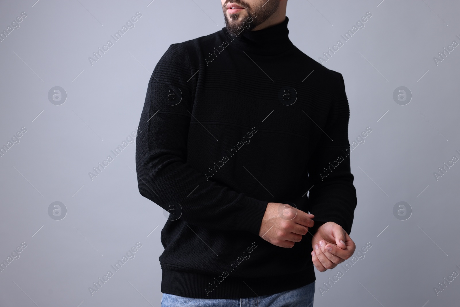 Photo of Man in stylish black sweater on grey background, closeup