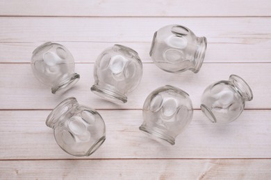 Photo of Glass cups on white wooden table, flat lay. Cupping therapy