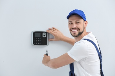 Photo of Male technician installing alarm system indoors