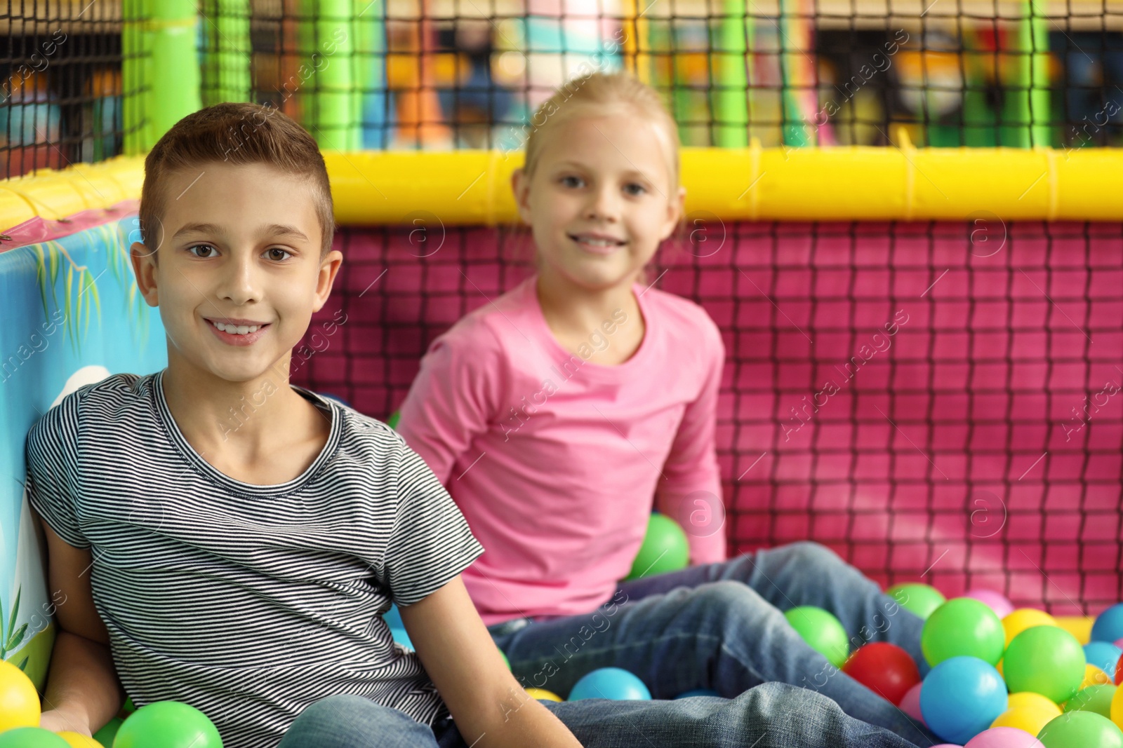 Photo of Cute little children playing in ball pit at indoor amusement park