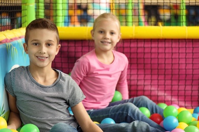 Photo of Cute little children playing in ball pit at indoor amusement park