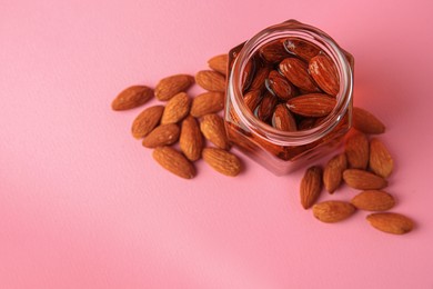 Photo of Jar with almonds and honey on pink background, above view. Space for text