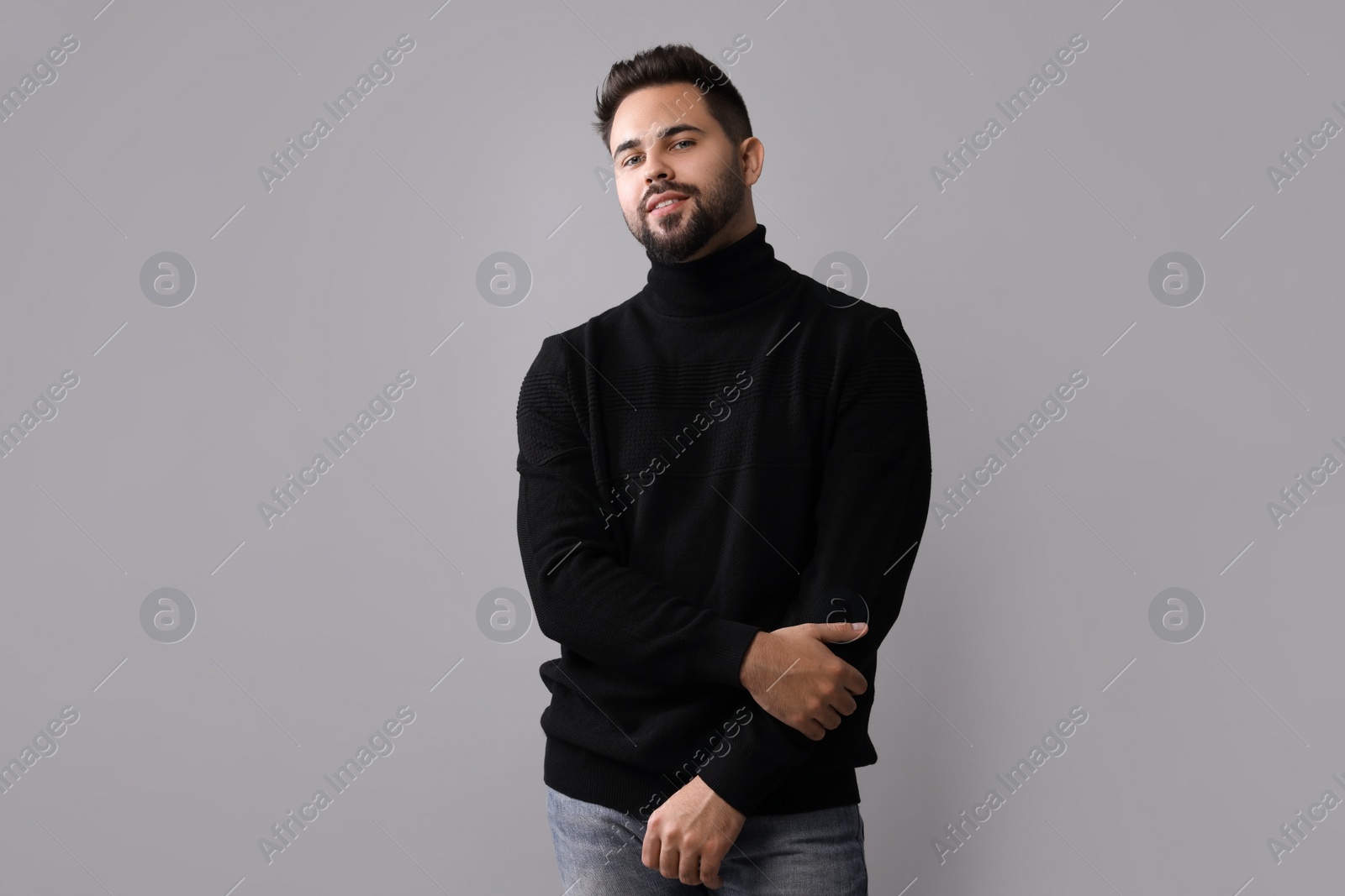 Photo of Handsome man in stylish black sweater on grey background