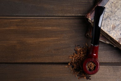 Photo of Smoking pipe, dry tobacco and old books on wooden table, flat lay. Space for text