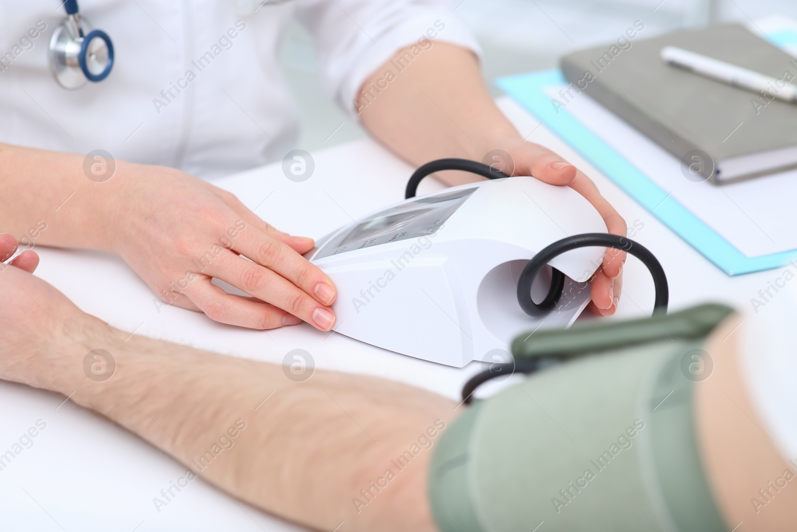 Photo of Doctor checking blood pressure of man in clinic, closeup