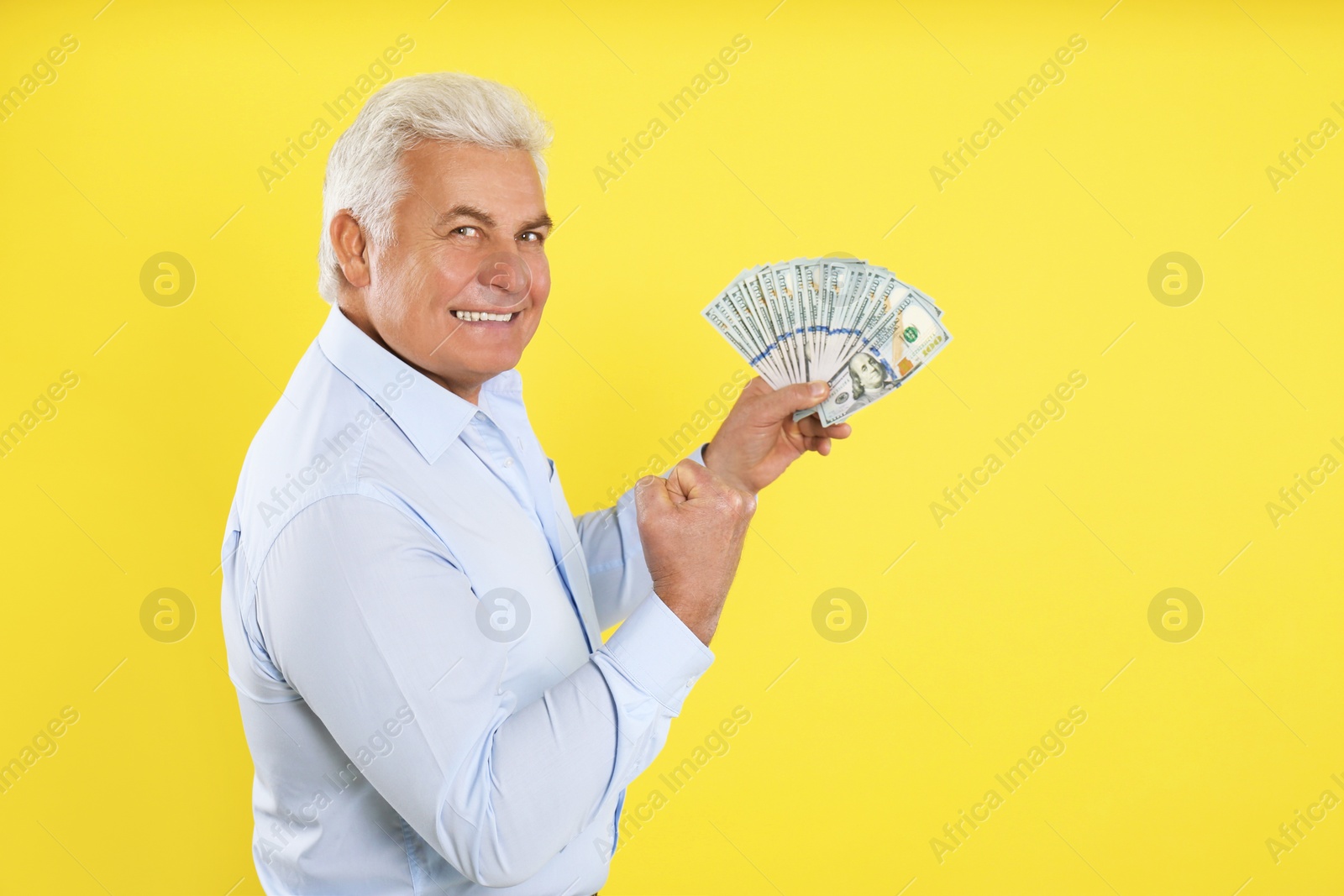 Photo of Emotional senior man with cash money on yellow background