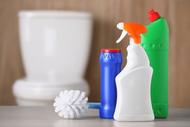 Bottles of cleaning products and toilet brush on table indoors