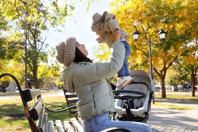 Happy mother with her baby son and stroller in park on autumn day