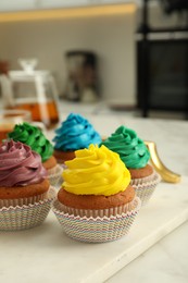 Delicious cupcakes with colorful cream on white board