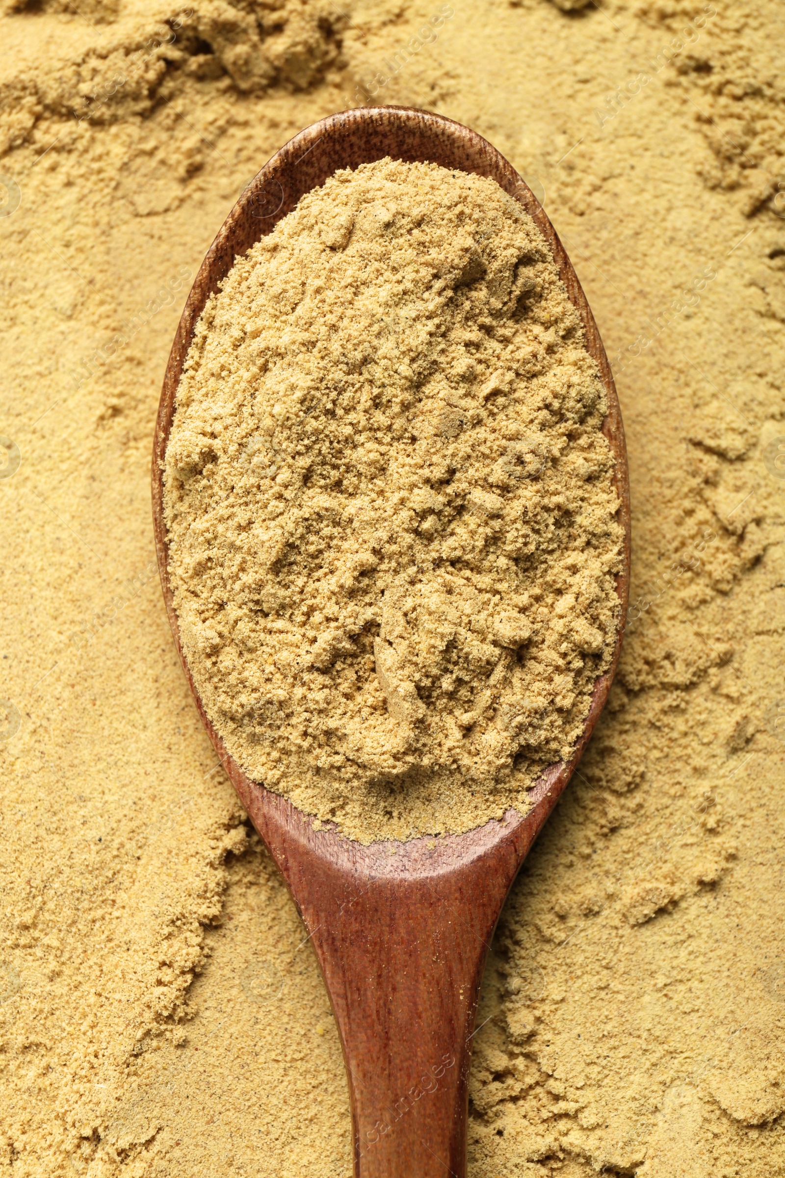 Photo of Heap of aromatic mustard powder and wooden spoon, top view