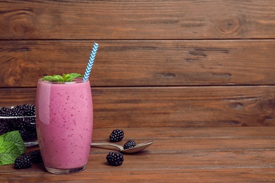 Photo of Glass of blackberry smoothie on wooden table. Space for text