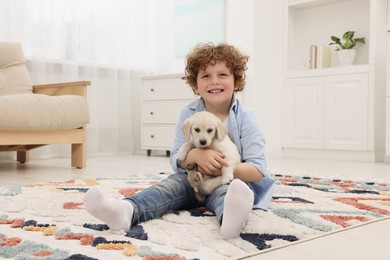 Photo of Little boy with cute puppy on carpet at home