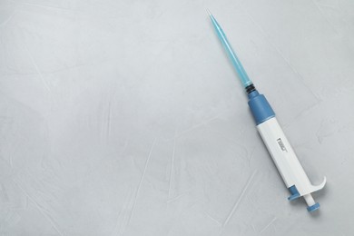 Photo of Laboratory analysis. Micropipette with liquid on grey table, top view. Space for text