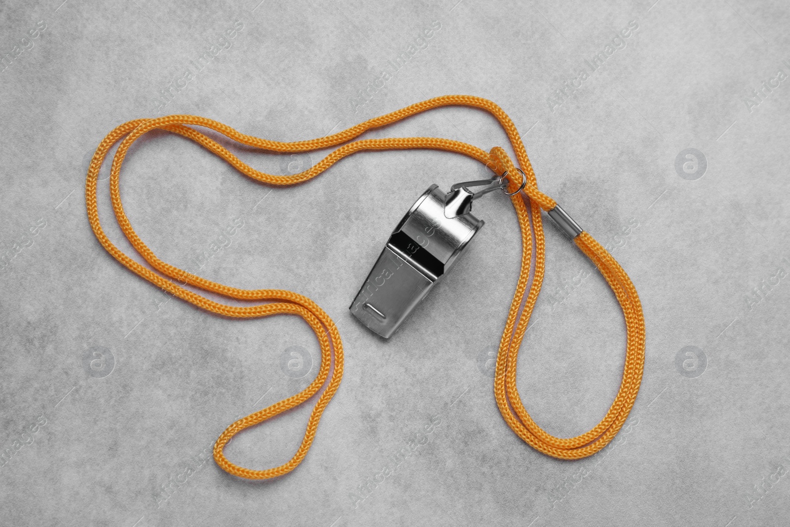 Photo of One metal whistle with cord on light grey table, top view