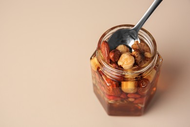 Photo of Jar with different nuts and honey on light table, space for text