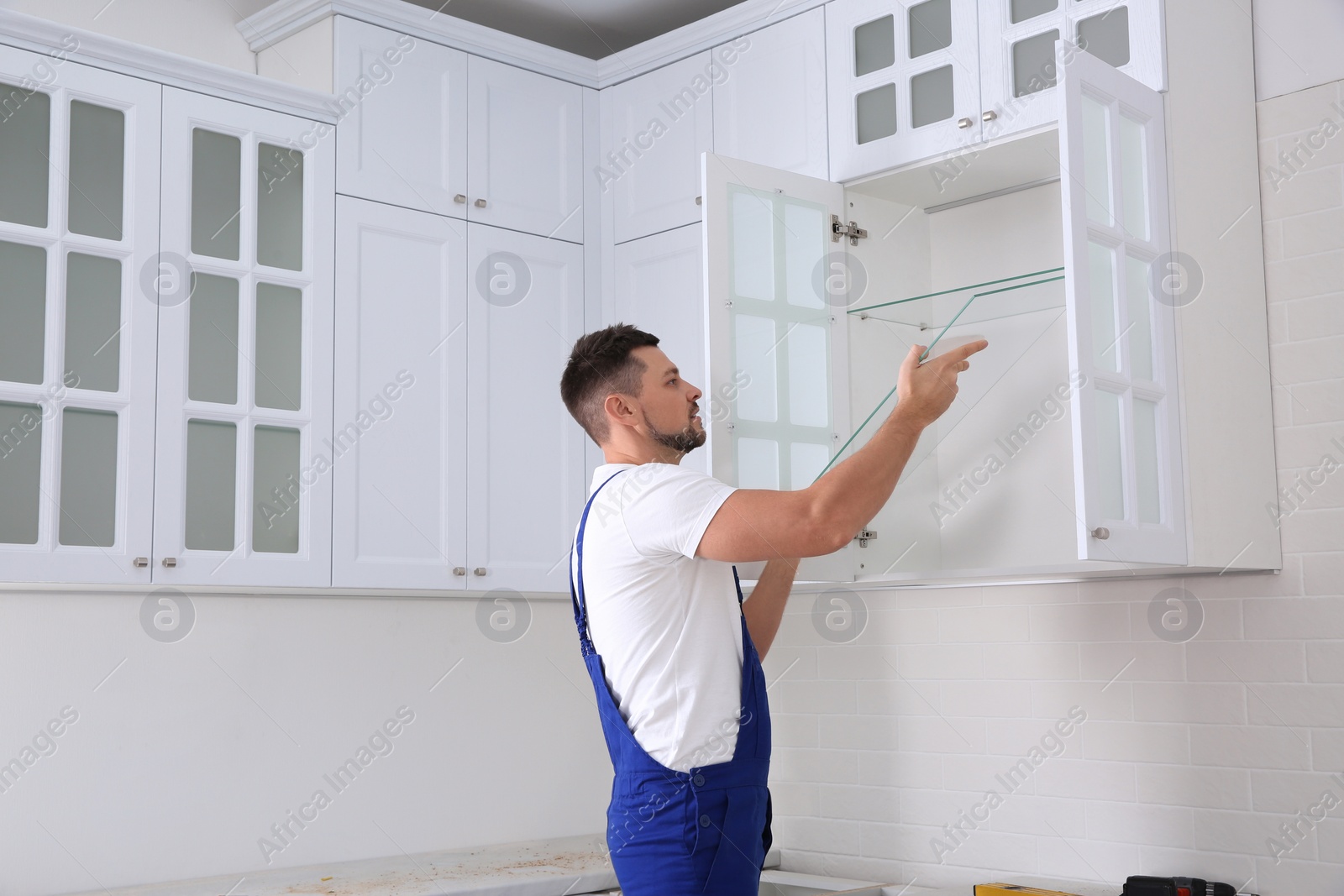 Photo of Worker installing cabinet with shelves in kitchen