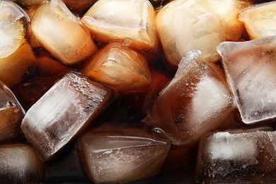 Closeup view of tasty refreshing cola with ice cubes as background