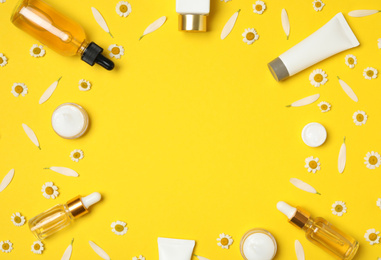 Photo of Flat lay composition with chamomiles and cosmetic products on yellow background. Space for text