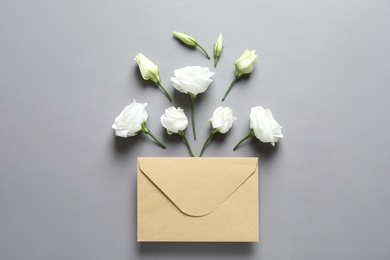 Photo of Beautiful Eustoma flowers and envelope on gray background