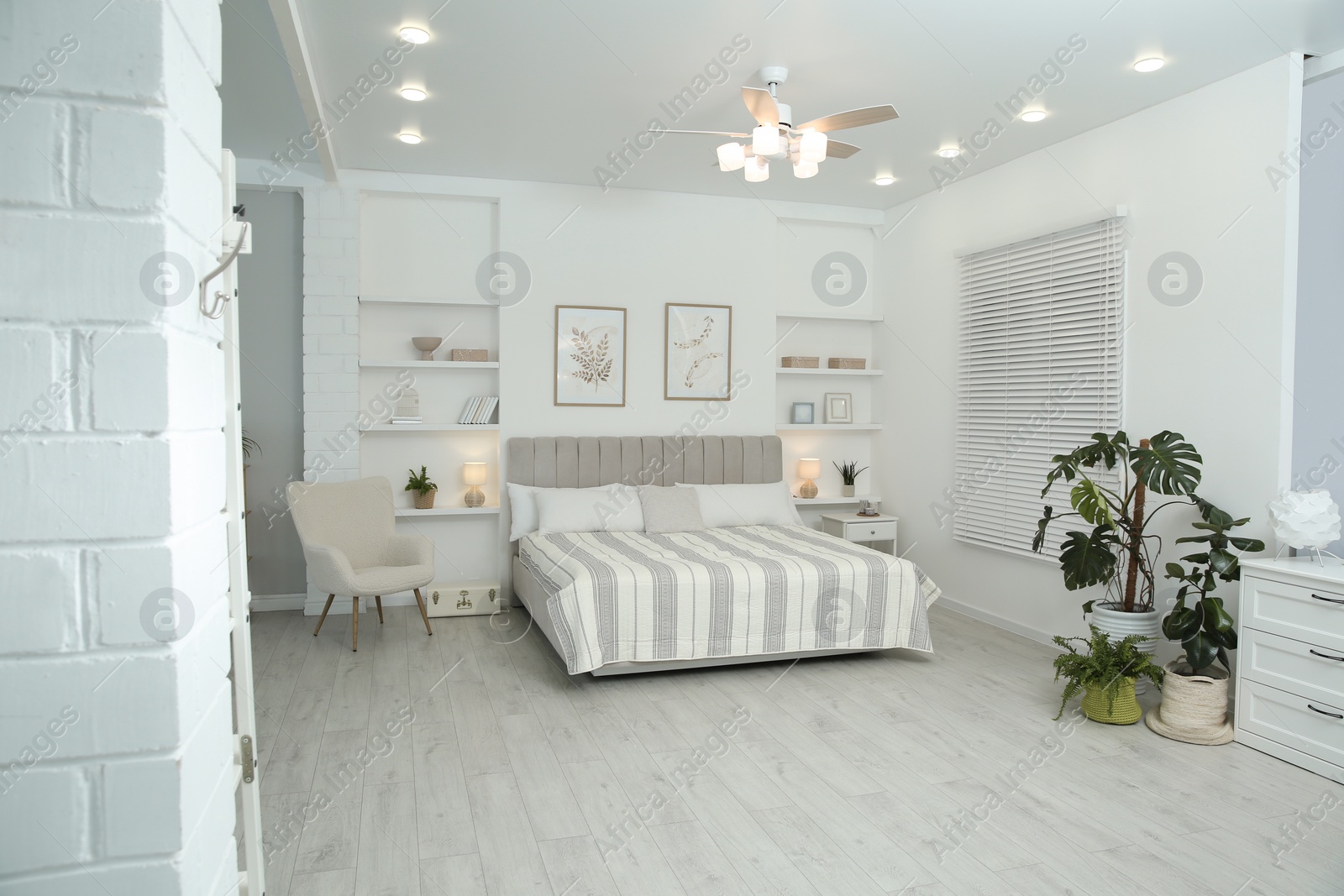 Photo of Comfortable furniture, ceiling fan, houseplants and accessories in stylish bedroom