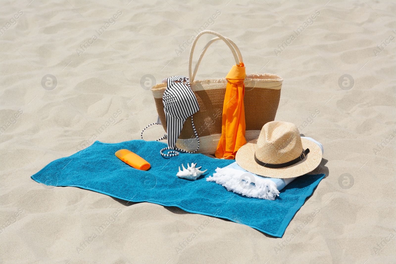 Photo of Blue towel, bag and accessories on sandy beach