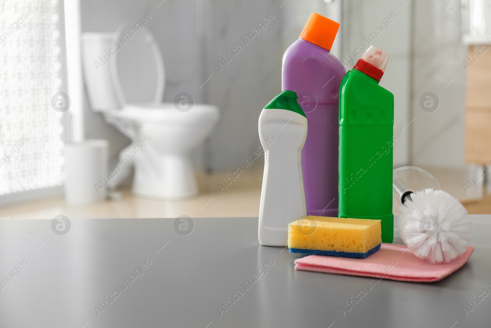 Photo of Cleaning supplies and toilet bowl in bathroom. Space for text