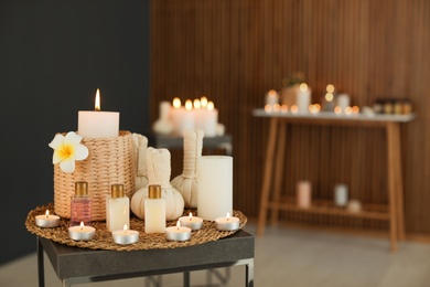 Photo of Beautiful composition with candles and spa accessories on table in salon. Space for text